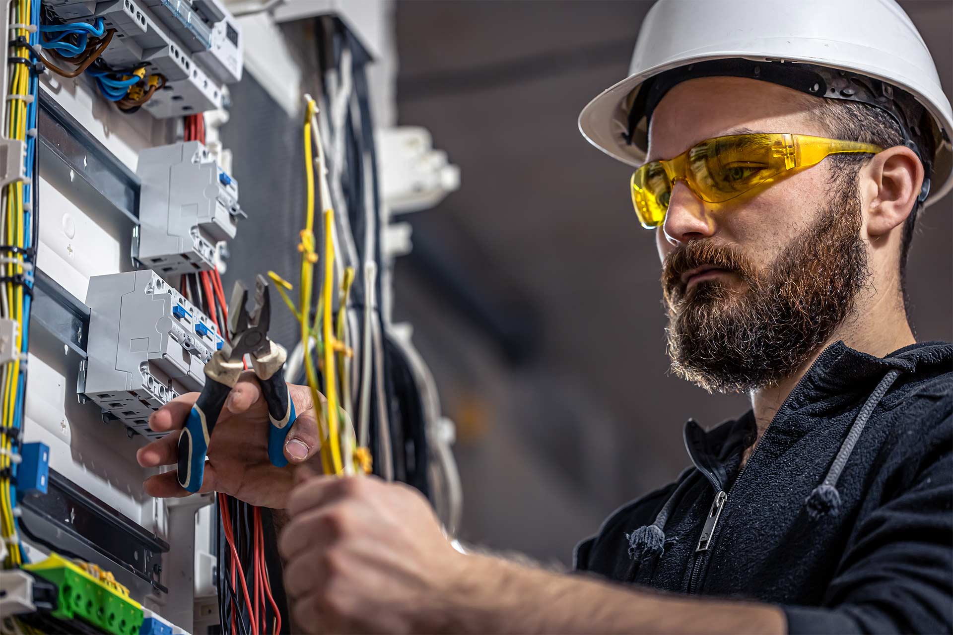 An electrician cutting the wires in the power station system.